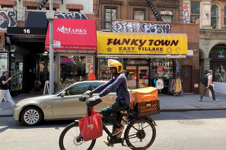 a guy on an e-bike passes an East Village store called Funky Town